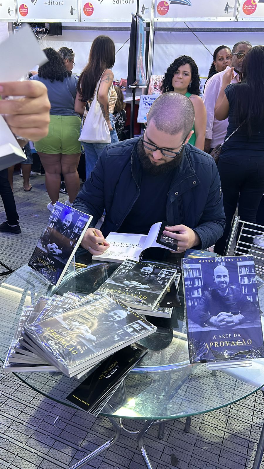 Prof. Mateus Teixeira autografando exemplares do livro A Arte da Aprovação na Feira Literária de Maricá